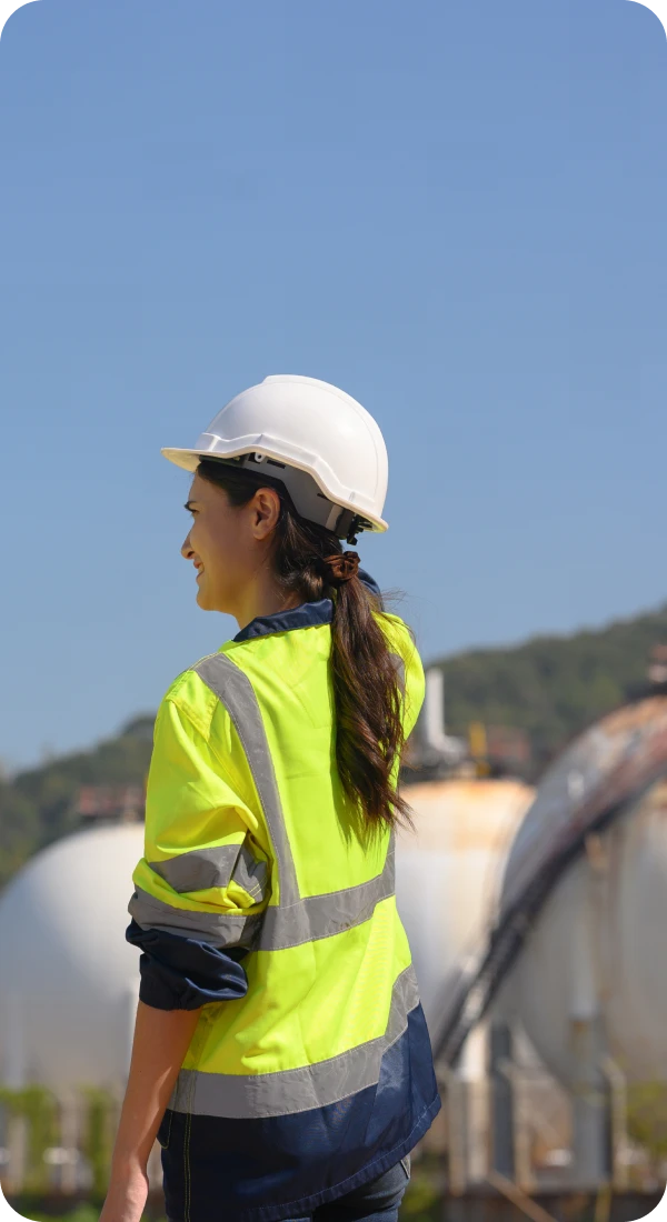 Woman in hard hat near storage tanks