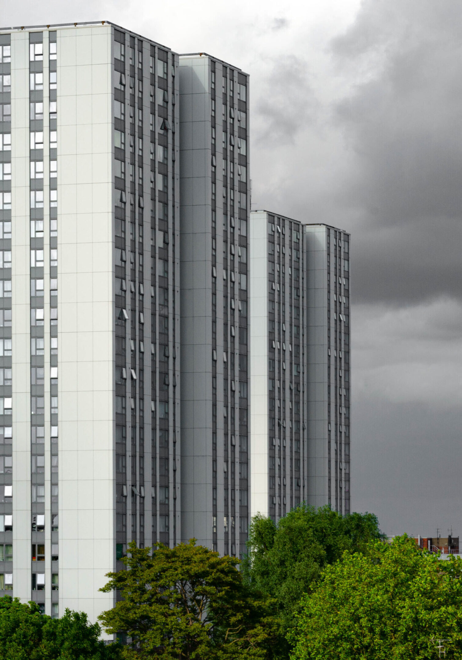 Ex local authority social housing high rise flats in north London, UK. Tower blocks stand tall basking in the late evening sun set against ominous black rain clouds.
