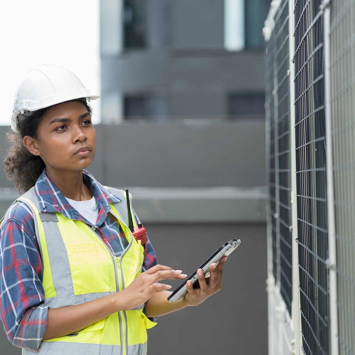 Female engineer or woman technician work with digital tablet for check or maintenance electrical system at construction site area. African American woman engineer management electrical system