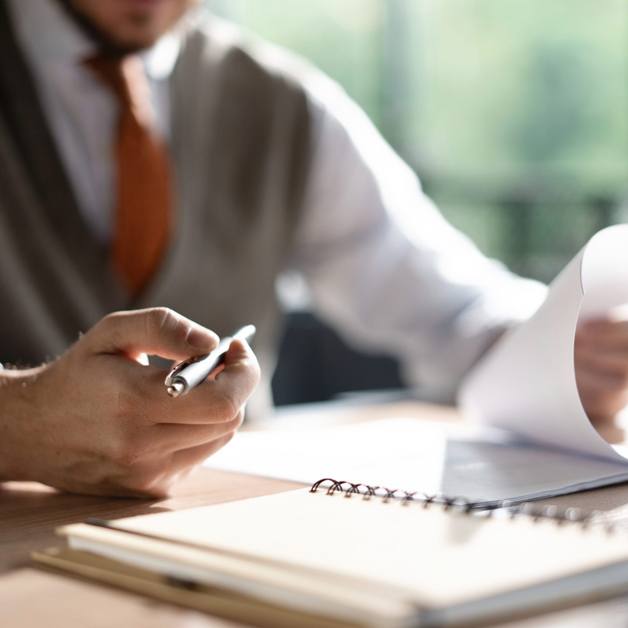 Businessman hands holding pen for working with stack of paper files, searching information, business report papers and piles of unfinished documents in modern office